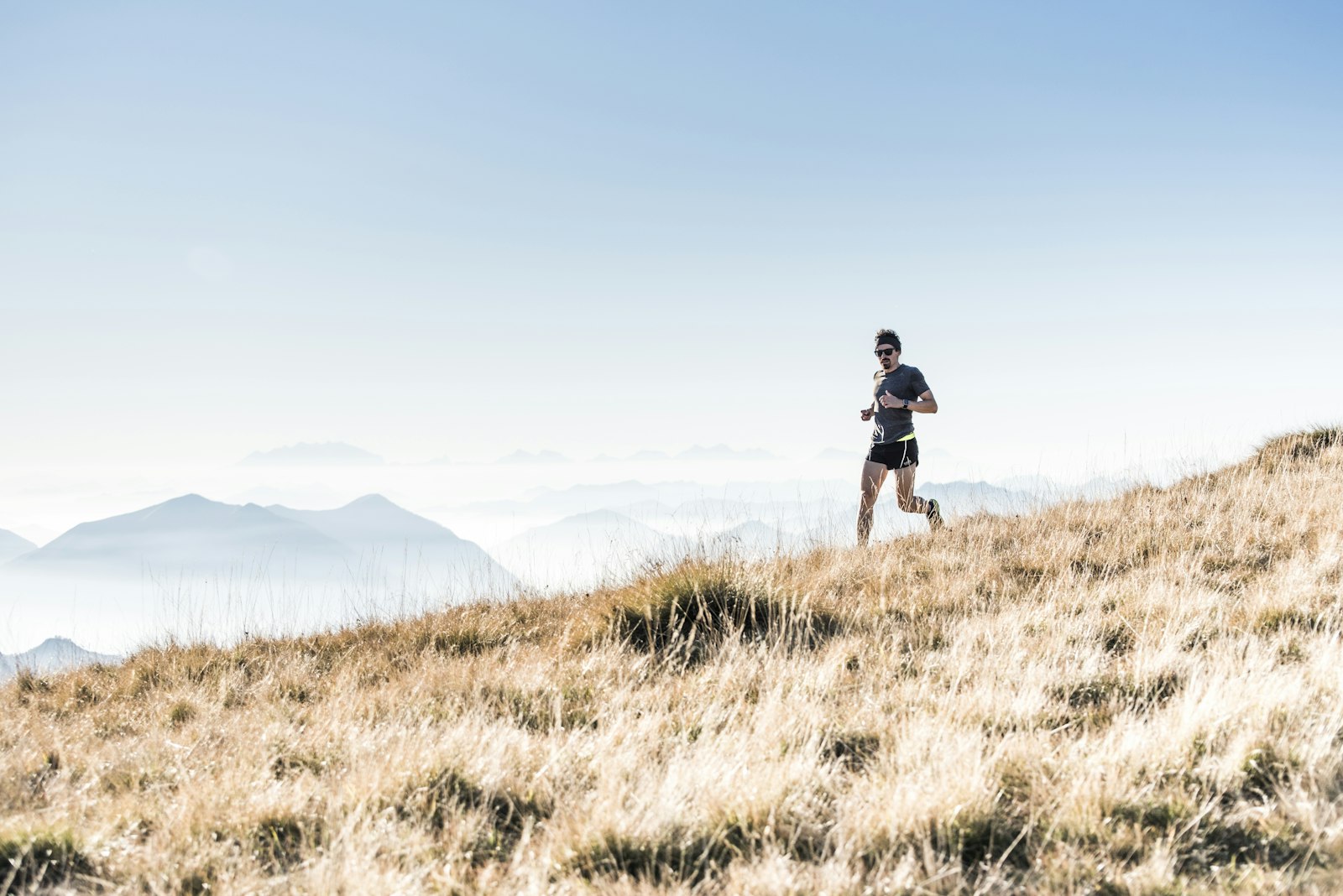 Runner on a grassy ridge above the clouds